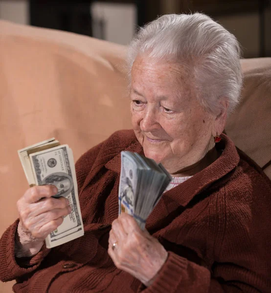 Vecchia donna dai capelli grigi sorridente in possesso di denaro contante dollaro — Foto Stock