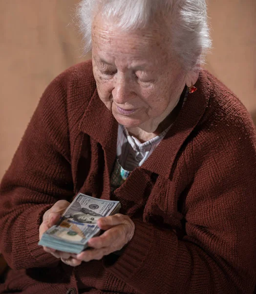 Vieille femme aux cheveux gris tenant de l'argent comptant en dollars — Photo