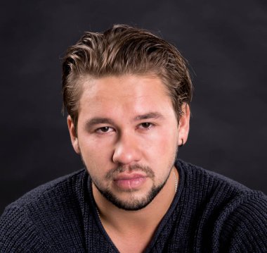 Akıllı ciddi genç adam bir siyah arka plan üzerinde poz