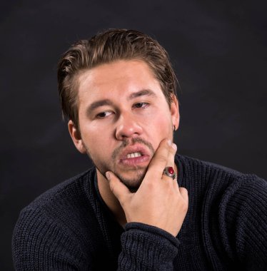 Akıllı ciddi genç adam bir siyah arka plan üzerinde poz