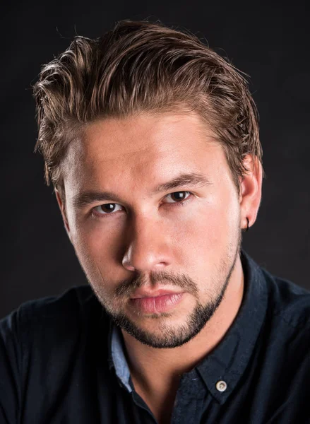 Smart serious young man posing on a black background — Stock Photo, Image