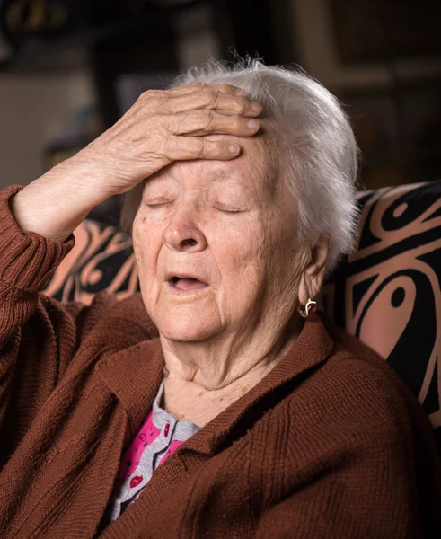 Старая седовласая женщина, страдающая от головной боли — стоковое фото