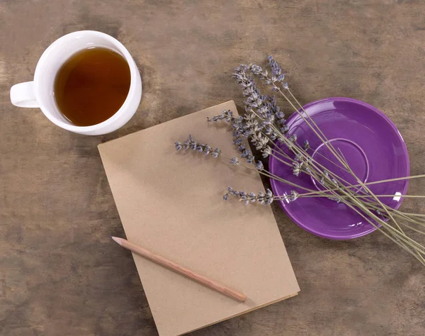 A cup of tea, lavender and notebook with pencil