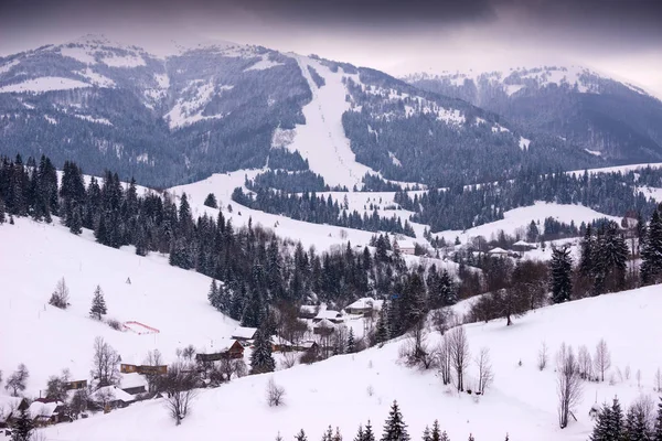 Winter mountain village landscape with snow and houses.