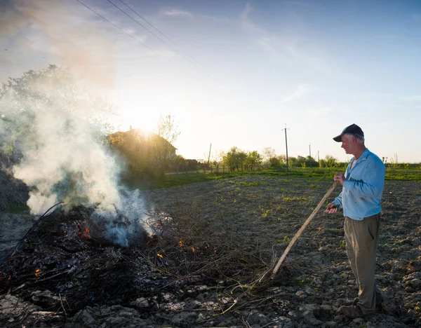 Lavora in giardino. Agricoltore che brucia rami secchi — Foto Stock