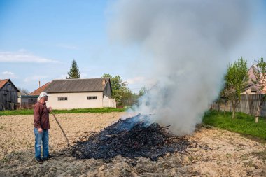 Bahçede çalışmak. Yanan çiftçi dalları kurutulmuş