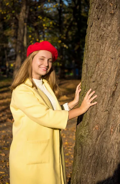 Sorridente adolescente bionda in cappotto giallo e berretto rosso all'aperto o — Foto Stock