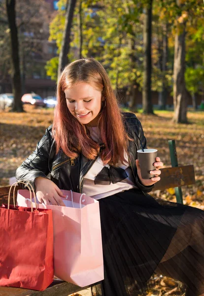 Happy teen girl holding takeaway coffee cups in sunny autumn par — Stock Photo, Image