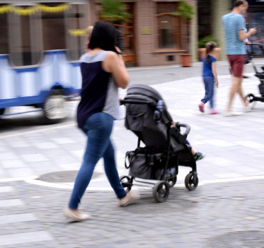 Bebek arabasında küçük çocuklu genç anne s aşağı yürüyor