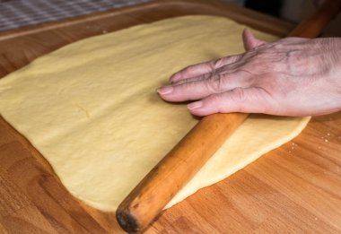 Daha fazla pişirmek için hamuru yuvarlayan kadın