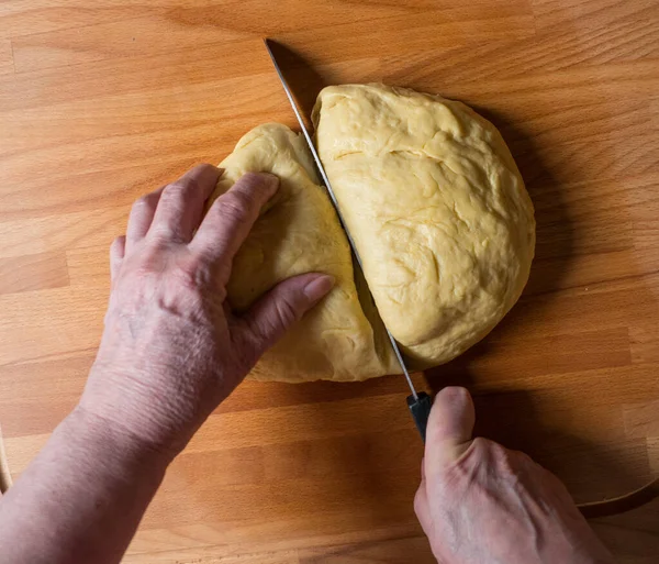 Жінка нарізає тісто на шматки для подальшого прокатки — стокове фото