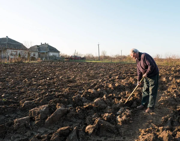 Contadino in piedi con una pala sul campo. Tempo primaverile — Foto Stock