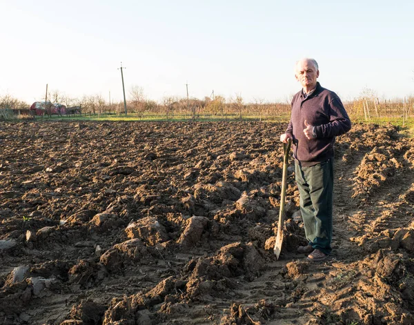 Agricultor de pie con una pala en el campo. Primavera — Foto de Stock