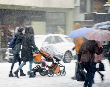 Şehir halkı kışın karlı bir günde cadde boyunca ilerliyorlar. İnt