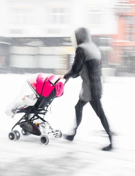 Vader wandelt met het kind in de wandelwagen op besneeuwde winterdag — Stockfoto