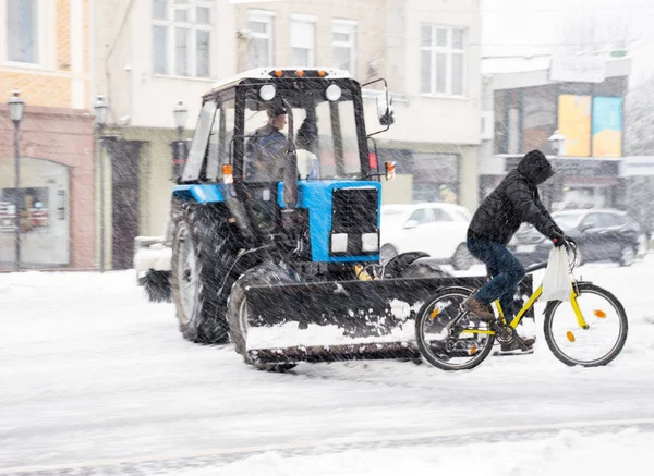Dangerous situation with snow removal machine and cyclist in sno — Stock Photo, Image