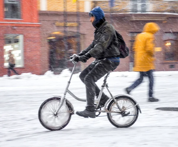 Rowerzysta na jezdni miasto w ruchu rozmycie. Zimowy śnieżny dzień — Zdjęcie stockowe