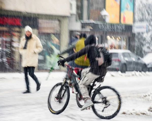 นักขี่จักรยานบนถนนในเมืองในการเคลื่อนไหวเบลอ วันหิมะฤดูหนาว — ภาพถ่ายสต็อก