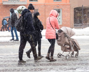 Yoğun şehir insanları kışın karlı bir günde cadde boyunca yürüyorlar.