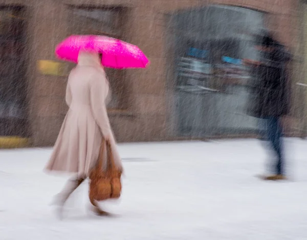 Frau mit Regenschirm läuft am Wintertag in mot die Straße entlang — Stockfoto