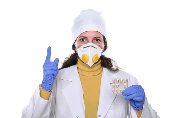 Médica feminina em máscara segurando pílulas em mãos sobre backgrou branco — Fotografia de Stock