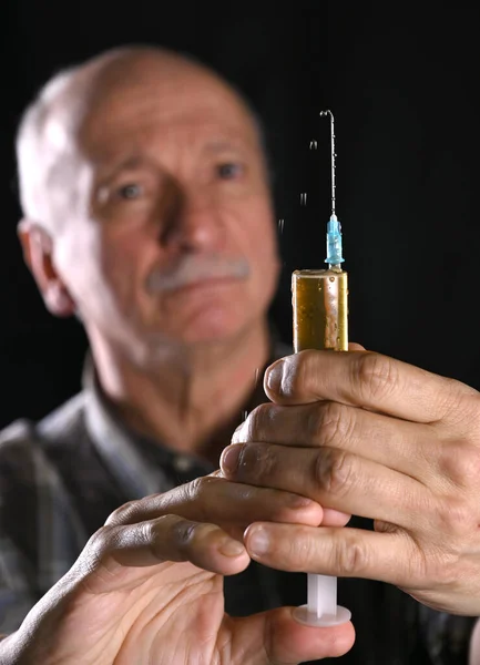 Senior man holding syringe over black background — Stock Photo, Image