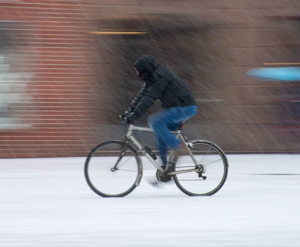 Чоловік на велосипеді в місті в сніжний зимовий день — стокове фото