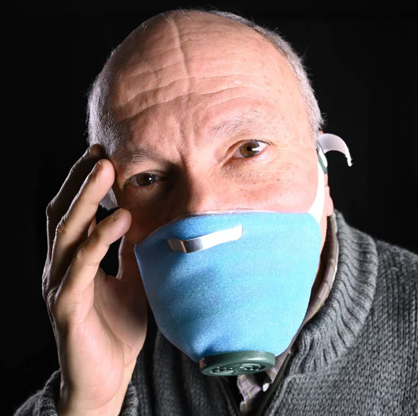 Kranker alter Mann posiert in Masken vor schwarzem Hintergrund — Stockfoto