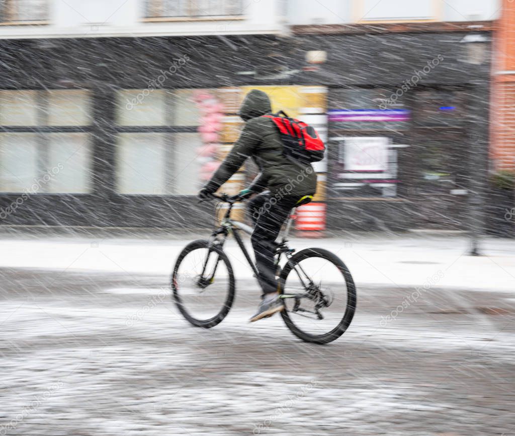 Cyclist on the city roadway on a rainy day in motion blur. Defocused image