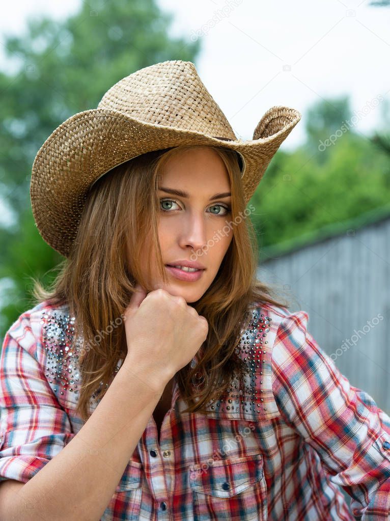 Portrait of young attractive cowgirl in hat posing outdoors