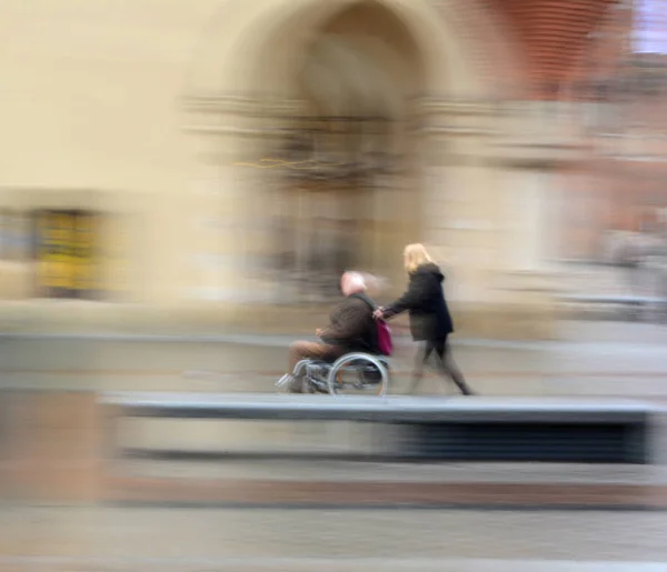 車椅子で男を突き動かす女がぼやける 専用画像 — ストック写真