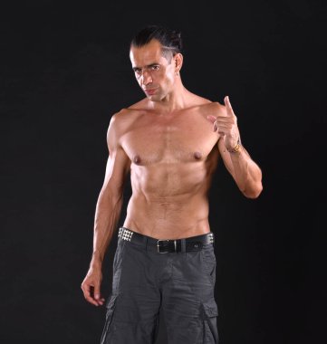 Koyu bir arka planda çıplak vücut pozu veren genç yakışıklı bir adam.