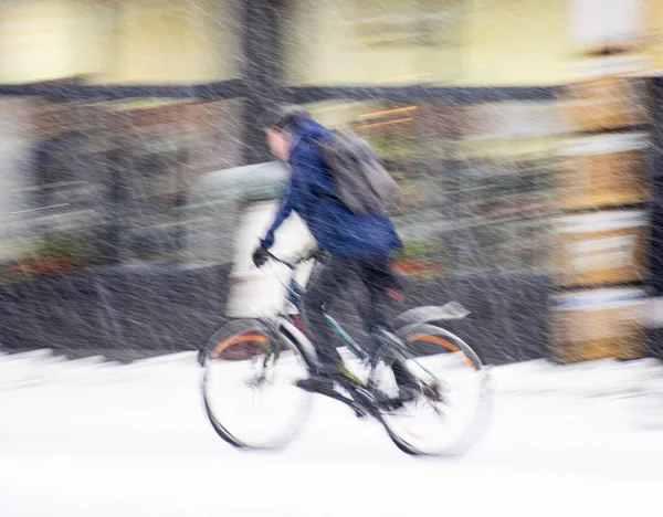 Cyclist on the city roadway on snowy day in motion blur. Defocused image
