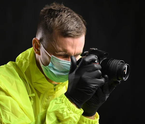 Coronavirus ve sağlık konsepti. Siyah arka planda kamera olan maskeli ve eldivenli genç bir adamın portresi