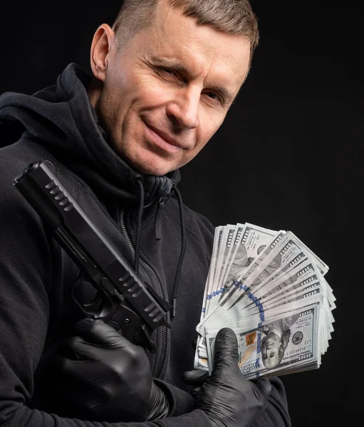 Siyah Kapüşonlu Silahlı Siyah Arka Planda Bir Çanta Dolusu Parası — Stok fotoğraf