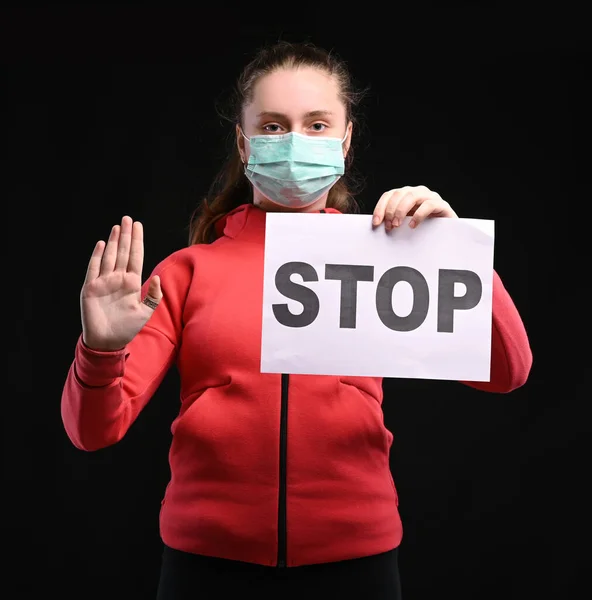 流行性コロナウイルスの概念 ティーン女の子で保護滅菌医療マスクオン彼女の顔ショーストップサイン以上黒の背景 — ストック写真