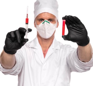 Maskeli doktor ve eldivenler beyaz arka planda kan olan test tüpü ve şırınga taşıyor. Salgın testi