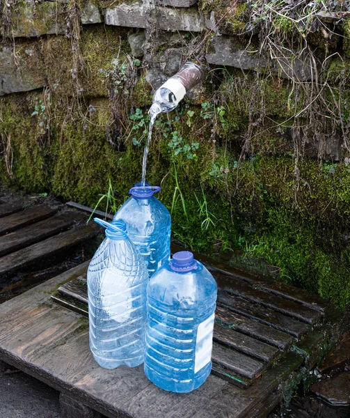 Filling fresh water from  mountain stream into plastic cans