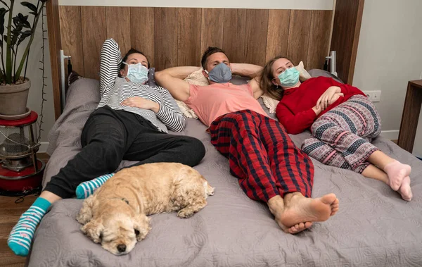 Healthcare concept. Sick family in protective masks  lying in bed at home