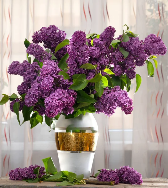Bouquet of purple lilac in vase on a table at home