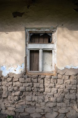 Terk edilmiş bir evin ön cephesinde eski kırık ahşap bir pencere.