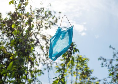 Bir koronavirüs salgını sırasında maske mavi gökyüzüne doğru uçar.