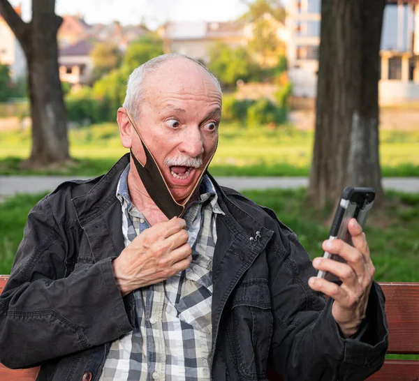 Šťastný Senior Muž Masce Obličeje Pomocí Smartphone Venku — Stock fotografie