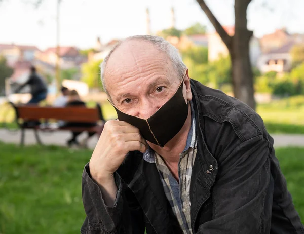 医療の概念 公園のベンチに座って保護顔のマスクのシニア男 — ストック写真
