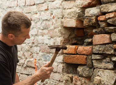  Eski taş duvarı yeniden inşa eden bir adam. Eski evin yeniden inşası, onarımı.