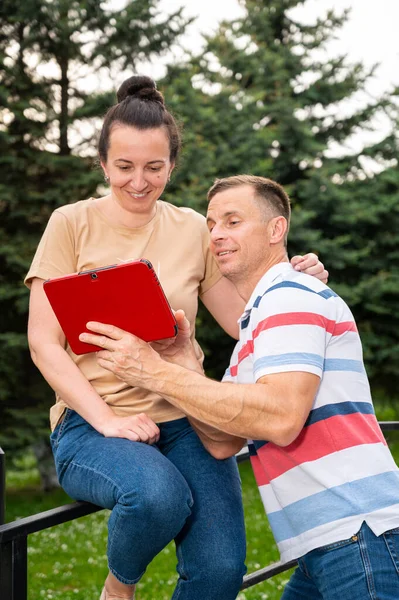 公園の屋外でデジタルタブレットを使用して幸せな笑顔のカップル — ストック写真