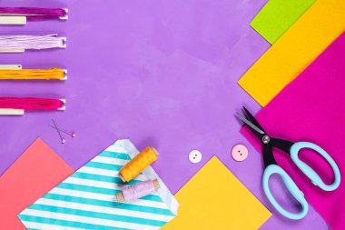 Çok renkli araç gereçleri var. Parlak bir arka planda ve kopyalama uzayı var. Dikiş dikmek, nakış işlemek ve el işi hobisi. İplik, düğme, iğne, kağıt torba, keçe, sciccors.