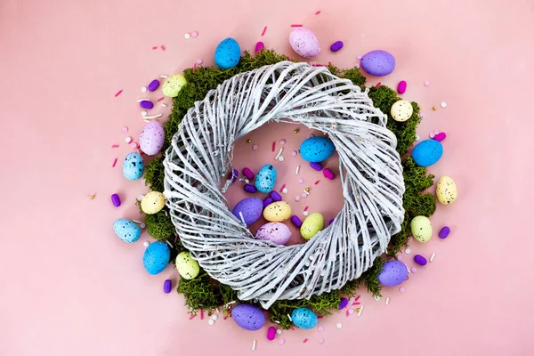 Top vista tiro de arranjo decoração Feliz feriado de Páscoa conceito de fundo. Grinalda plana de galhos e ovos de coelho coloridos na bela mesa rosa . — Fotografia de Stock