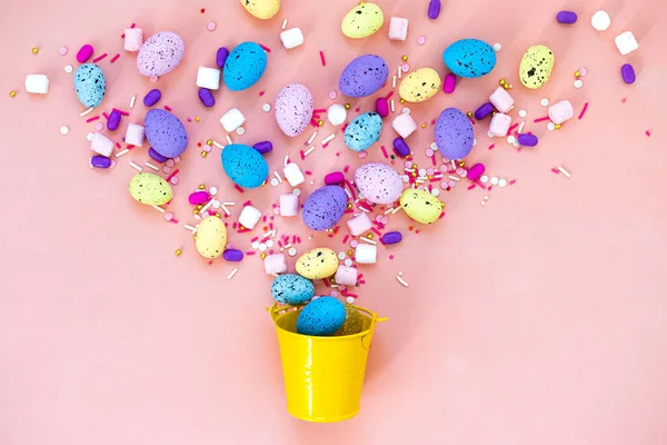 Top vista tiro de arranjo decoração Feliz feriado de Páscoa conceito de fundo. Os ovos de coelho coloridos postos chatos em um balde amarelo na mesa rosa. Caça aos ovos . — Fotografia de Stock