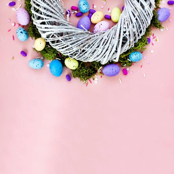 Top vista tiro de arranjo decoração Feliz feriado de Páscoa conceito de fundo. Grinalda plana de galhos e ovos de coelho coloridos na bela mesa rosa . — Fotografia de Stock